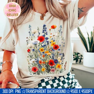 May include: A white t-shirt with a colorful floral print featuring red, yellow, blue, and white flowers. The flowers are arranged in a bouquet-like design.