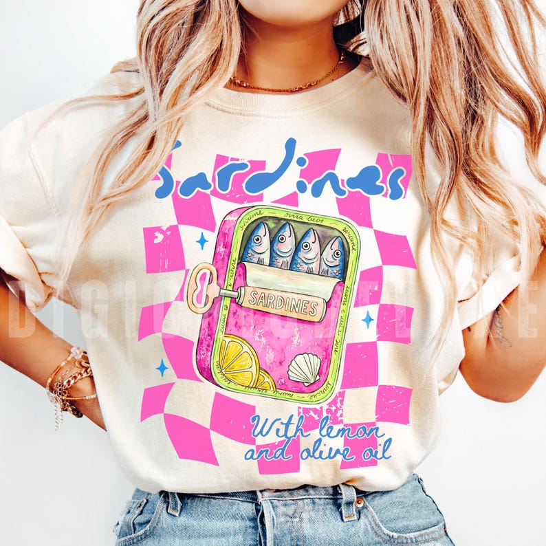 Trendy sardines shirt design featuring a pink illustrated sardine tin can with fish, lemon slices, shell detail, blue lettering, and hot pink checkerboard background. Cute Mediterranean foodie graphic perfect for coastal Europe vacations, European summer outfits design, fish market aesthetic, seafood lover gifts, retro vacation shirts design, beach trip apparel design, coastal boutique fashion, and trendy graphic shirt design for women, girls trips, and summer travel. For sublimation and DTF.