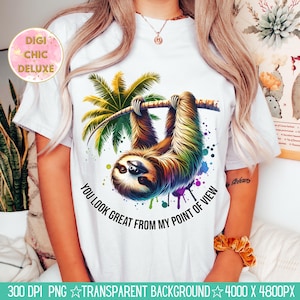 May include: White t-shirt featuring a colorful illustration of a sloth hanging from a tree branch with palm leaves. The text "YOU LOOK GREAT FROM MY POINT OF VIEW" is printed below the sloth. The shirt has a round neck.