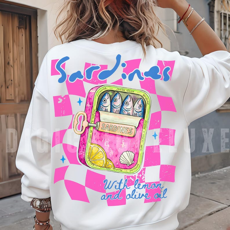 Trendy sardines shirt design featuring a pink illustrated sardine tin can with fish, lemon slices, shell detail, blue lettering, and hot pink checkerboard background. Cute Mediterranean foodie graphic perfect for coastal Europe vacations, European summer outfits design, fish market aesthetic, seafood lover gifts, retro vacation shirts design, beach trip apparel design, coastal boutique fashion, and trendy graphic shirt design for women, girls trips, and summer travel. For sublimation and DTF.