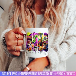 May include: White ceramic mug with a colorful design featuring sugar skulls, a guitar, a margarita glass, and the text "Cinco de Mayo".