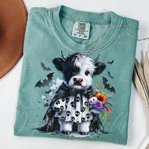 Adorable baby Highland cow in a black skull cape and spooky dress, holding a colorful fall bouquet with a skull plush. This cute Halloween cow PNG design is perfect for sublimation, fall clipart, kids Halloween shirt designs, printable wall art, spooky cute decor, cow lover gifts, and gothic autumn apparel. Great for tees, sweaters, mugs, and farmhouse Halloween crafts.
