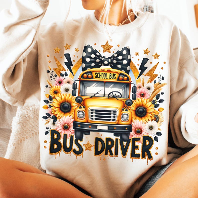 May include: A white sweatshirt with a yellow school bus graphic, a black and white polka dot bow, sunflowers, and the text "BUS DRIVER" in gold glitter.