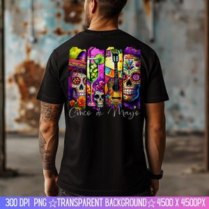 May include: Black t-shirt with a colorful graphic design featuring a guitar, a glass of margarita, and sugar skulls. The text "Cinco de Mayo" is printed below the graphic.