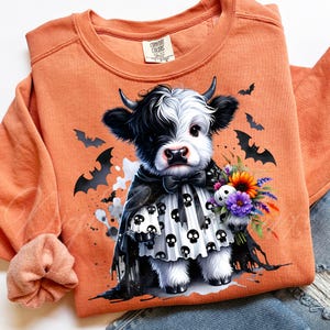 Adorable baby Highland cow in a black skull cape and spooky dress, holding a colorful fall bouquet with a skull plush. This cute Halloween cow PNG design is perfect for sublimation, fall clipart, kids Halloween shirt designs, printable wall art, spooky cute decor, cow lover gifts, and gothic autumn apparel. Great for tees, sweaters, mugs, and farmhouse Halloween crafts.
