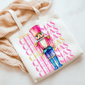 Hand-painted watercolor nutcracker soldier Christmas PNG design in vibrant pink, gold, and blue with festive stars and layered “Merry Christmas” lettering. Perfect for holiday shirts, Christmas party outfits, Nutcracker ballet gifts, winter home décor, festive wall art, seasonal apparel, cozy holiday decorations, and Christmas gift ideas for women and kids.