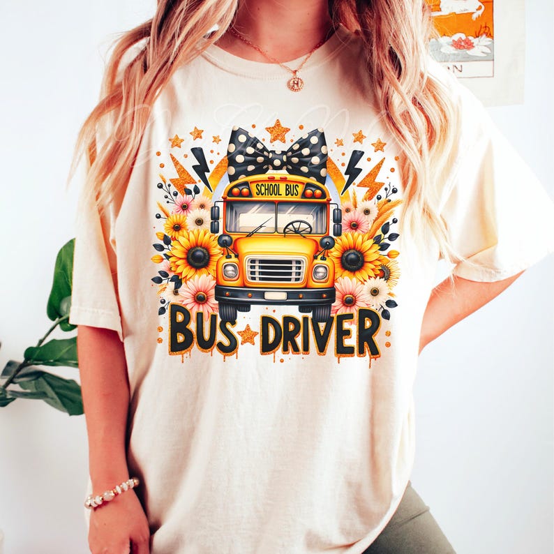 May include: A white t-shirt with a yellow school bus graphic, a black and white polka dot bow, and the text "Bus Driver" in black. The bus is surrounded by sunflowers and other flowers.