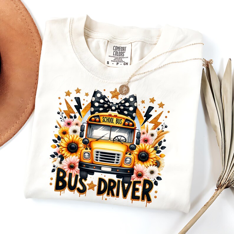 May include: A white t-shirt with a yellow school bus graphic, sunflowers, and a black and white polka dot bow. The text "School Bus" and "Bus Driver" are printed on the shirt.