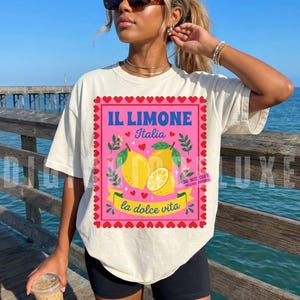 Pink Italian lemon shirt PNG design featuring bold yellow lemons, heart scalloped border, “Il Limone Italia” and “La Dolce Vita” text in retro Mediterranean style. Amalfi Coast aesthetic graphic tee design, lemoncore fashion, Italian summer shirt design, Italy vacation shirt, cute Europe travel apparel, feminine coastal citrus art, Italy lover gift, Lemon wall art, Mediterranean fruit illustration PNG clipart design.