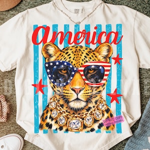 Patriotic leopard PNG design featuring glamorous leopard wearing American flag sunglasses and chunky gold jewelry on retro blue striped background. Trendy USA coquette animal graphic perfect for 4th of July shirts, patriotic apparel, summer vacation tees, western glam fashion, Independence Day party outfit, leopard lover gift, sublimation PNG, DTF transfer, print on demand design, tumbler wrap, mug design, wall art printable, boutique graphic tee, trendy Americana aesthetic clipart.