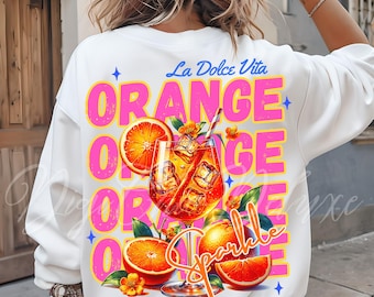 May include: White sweatshirt with a colourful graphic design. It features an orange cocktail with ice, orange slices, and the words "Orange" and "Sparkle" in pink and orange. The phrase "La Dolce Vita" is above the design.