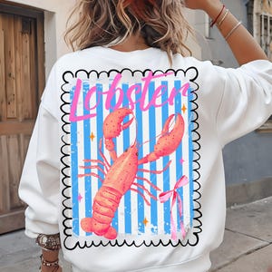 Bold watercolor lobster design with pink bow on nautical blue and white stripes — perfect for coastal cowgirl aesthetic, seafood lovers, Maine lobster festival gifts, retro summer beach vibes, ocean-themed apparel, and girly cottagecore fans. Trendy crustacean print for quirky fashion, East Coast preppy style, Y2K nautical chic, or seaside travel souvenir. Great for lobster parties, boating outfits, or colorful graphic tees with a fun foodie twist.