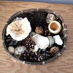 May include: A woven basket filled with natural elements, including pinecones, dried mushrooms, and a small wooden bowl.