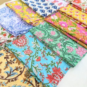 May include: A stack of colourful fabric napkins with floral patterns. The napkins are made of cotton and are ideal for adding a touch of elegance to any table setting.