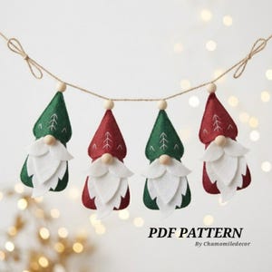 Pode incluir: Uma guirlanda com quatro ornamentos de gnomos de feltro pendurados em um cordão. Os gnomos têm gorros pontiagudos em cores vermelha e verde alternadas com detalhes costurados em branco, narizes de contas de madeira e barbas de feltro branco.