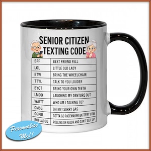 May include: A white ceramic mug with a black handle and rim. The mug features the text "SENIOR CITIZEN TEXTING CODE" with a list of acronyms and their meanings. Includes illustrations of an elderly man and woman.