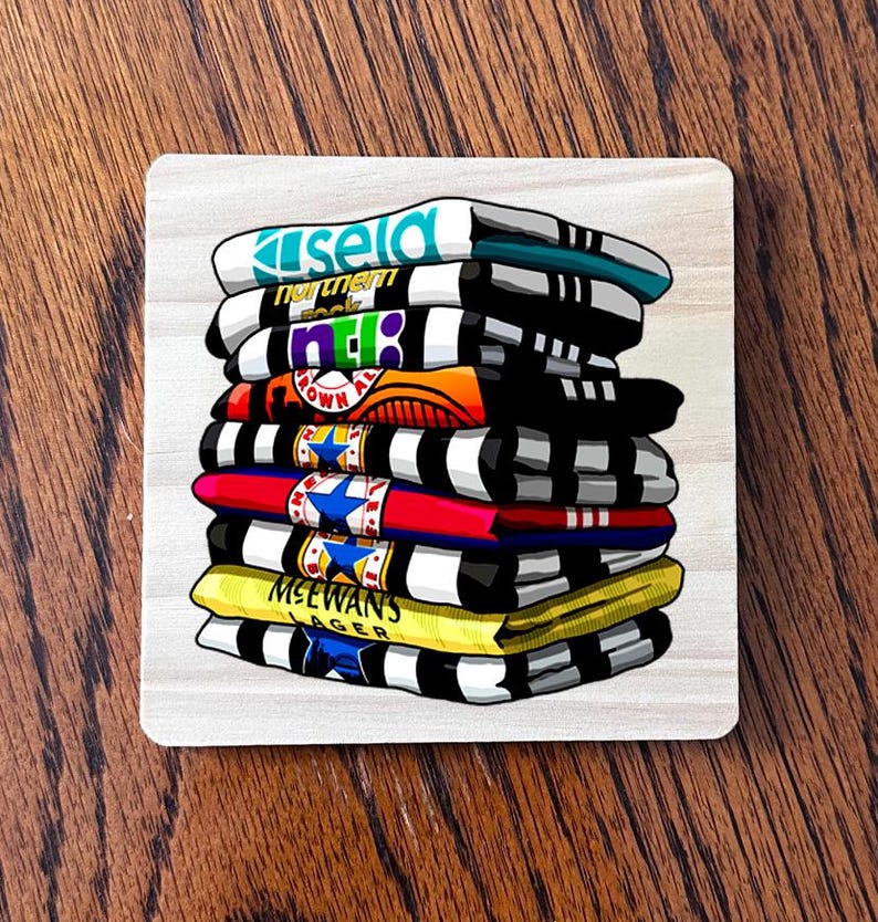May include: A square coaster with a stack of illustrated shirts. The shirts are in various colors, including white, black, yellow, red, and blue. Each shirt has a different logo or text, such as "Kisela" and "McEwan's Lager".