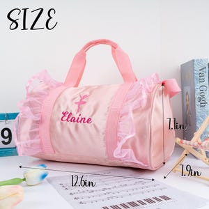 May include: Pink ballerina dance bag with a ruffled trim and the name "Elaine" embroidered on the front. The bag measures 12.6 inches long, 7.1 inches wide, and 1.9 inches high.