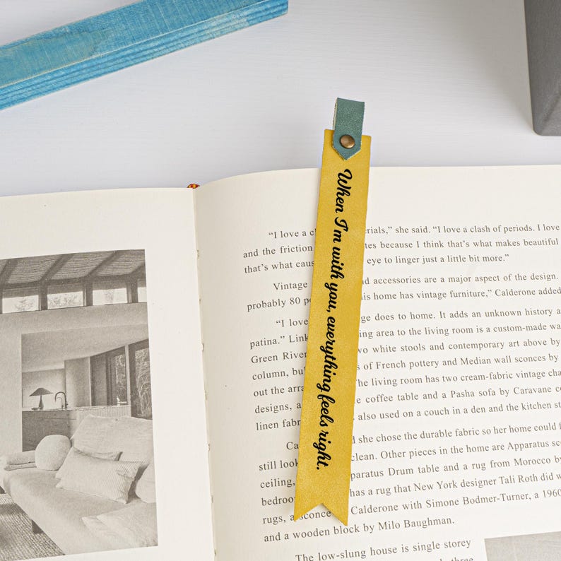 Puede incluir: Un marcap&aacute;ginas de cuero amarillo con el texto "When I'm with you, everything feels right." El marcap&aacute;ginas est&aacute; atado con una cinta azul.