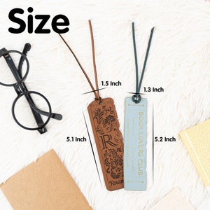 May include: Two leather bookmarks with a brown and blue color scheme. The brown bookmark is 5.1 inches long and 1.5 inches wide. The blue bookmark is 5.2 inches long and 1.3 inches wide. The brown bookmark has a decorative design and the text "Rnan" and the blue bookmark has the text "BOOK LOVERS CLUB" and "Good book is a good friend."