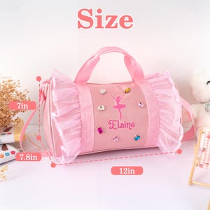 Peut inclure: Sac de ballet rose avec un graphisme de ballerine et le nom "Elaine". Le sac mesure 30.5 cm de long, 17.8 cm de haut et 19.8 cm de large. Il pr&eacute;sente une garniture &agrave; volants et des bijoux d&eacute;coratifs.