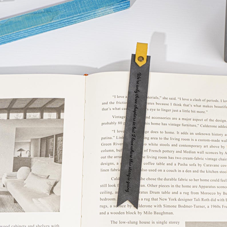 Puede incluir: Un marcap&aacute;ginas de cuero negro con una leng&uuml;eta de cuero amarillo. El marcap&aacute;ginas tiene el texto "We're only three chapters in but I love where this story is going" impreso en &eacute;l.