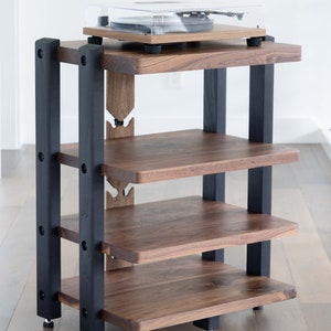 May include: A four-shelf audio rack made of walnut wood with black painted metal supports. The rack has a turntable on the top shelf.