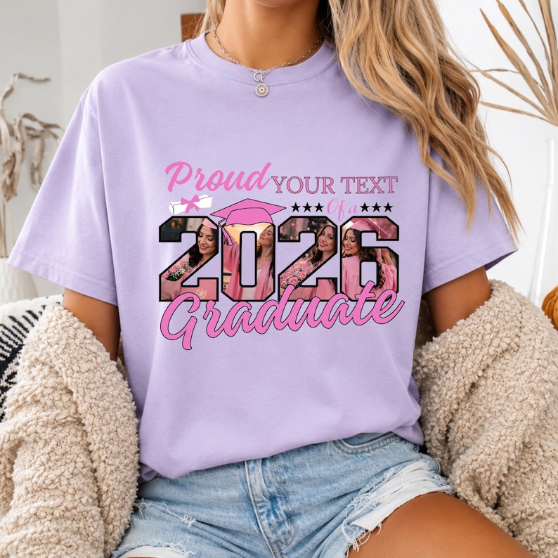 May include: A light purple t-shirt with the text "Proud YOUR TEXT of a 2026 Graduate" in pink. The numbers 2026 are filled with a photo of a person wearing a graduation cap. The shirt has short sleeves.