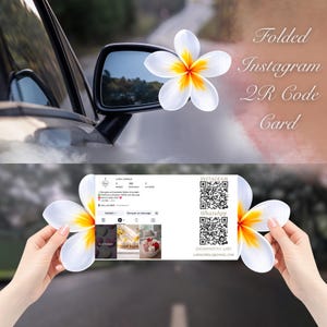 May include: A folded Instagram QR code card featuring a white and yellow plumeria flower design. The card displays an Instagram profile with a QR code for WhatsApp and the text "Lara Candle". The background shows a car mirror and a road.