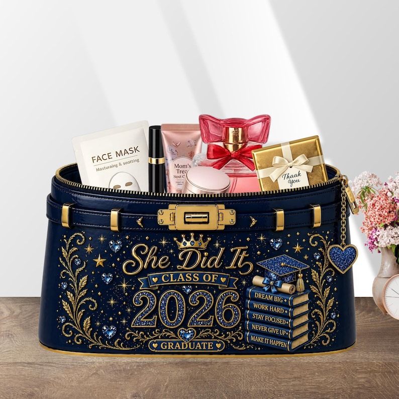 May include: A navy blue cosmetic bag with gold accents and the text "She Did It Class of 2026 Graduate." The bag is filled with beauty products, including a face mask, perfume, and a gift box. A graduation cap and books are also featured.