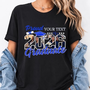 May include: Black t-shirt with a graduation theme. The design includes the words "Proud" and "Graduate" in blue script, along with the year "2026" and space for custom text. The shirt features images of graduates.