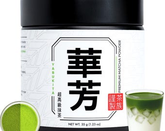 Puede incluir: Un bote cilíndrico negro de polvo de matcha premium Yabukita con una etiqueta blanca que presenta grandes caracteres japoneses negros, el texto "PREMIUM MATCHA POWDER" y "NET WT. 35 g (1.23 oz)". Se muestran un cuenco de polvo verde y un vaso de matcha latte helado.