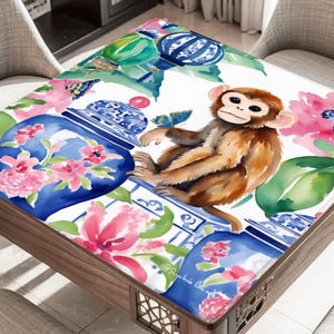 May include: A square table with a decorative top featuring a watercolor design. The design includes a brown monkey, blue butterflies, pink flowers, and blue and white vases. The table has a wooden frame.