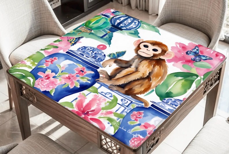 May include: A square table with a decorative top featuring a watercolor design. The design includes a brown monkey, blue butterflies, pink flowers, and blue and white vases. The table has a wooden frame.