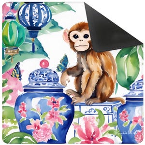 May include: A decorative mat featuring a watercolor design with a brown monkey, blue and white porcelain jars, pink flowers, and blue butterflies. The background includes green foliage and blue lanterns. The mat has a black, non-slip backing.