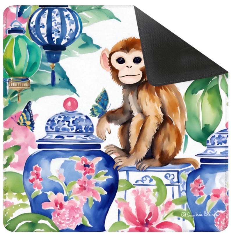 May include: A decorative mat featuring a watercolor design with a brown monkey, blue and white porcelain jars, pink flowers, and blue butterflies. The background includes green foliage and blue lanterns. The mat has a black, non-slip backing.