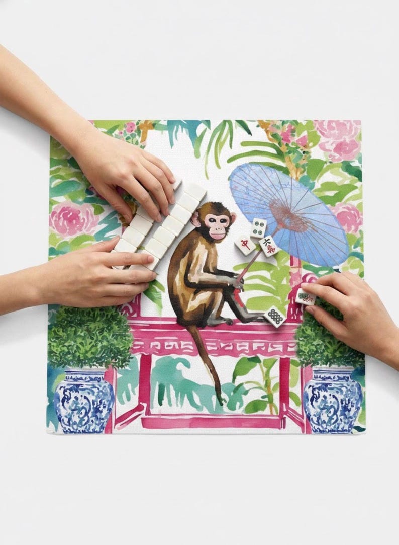 K&ouml;nnte beinhalten: Bunte Illustration eines Affen, der Mahjong spielt. Der Affe ist braun und sitzt auf einer rosa Struktur mit floralem und laubartigem Hintergrund. Ein blauer Sonnenschirm und blau-wei&szlig;e Vasen sind ebenfalls zu sehen.