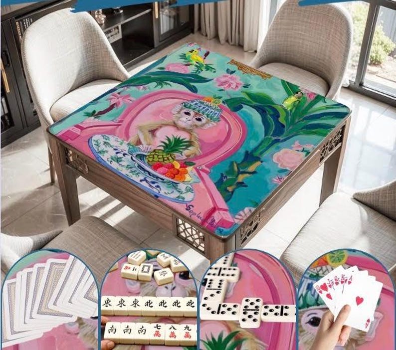 May include: A wooden game table with a colorful, artistic design featuring a monkey, fruit, and floral elements. The table is surrounded by four chairs. The table's surface is a vibrant mix of pink, teal, and green.