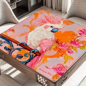 May include: A square wooden table with a vibrant, artistic design. The tabletop features a painting of a pink and white cockatoo perched on a branch with pink flowers against an orange and pink background. The table has a decorative wooden frame.