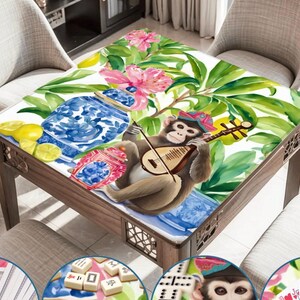 Puede incluir: Una mesa cuadrada de madera con un dise&ntilde;o colorido y caprichoso. La superficie de la mesa presenta un mono tocando un la&uacute;d, rodeado de flores, limones y jarrones de porcelana azul y blanca. La mesa est&aacute; rodeada de sillas.