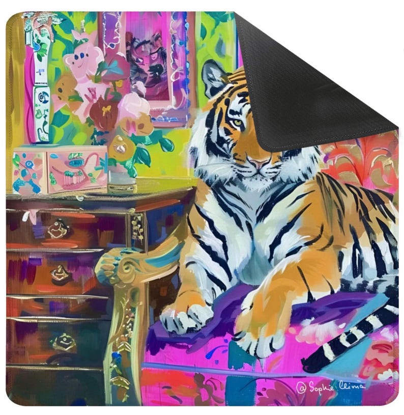 May include: A colorful mouse pad featuring a tiger resting on a pink chair. The tiger has orange and black stripes. The background includes a dresser, flowers, and a window with a tiger image. The artist's signature is in the bottom right corner.