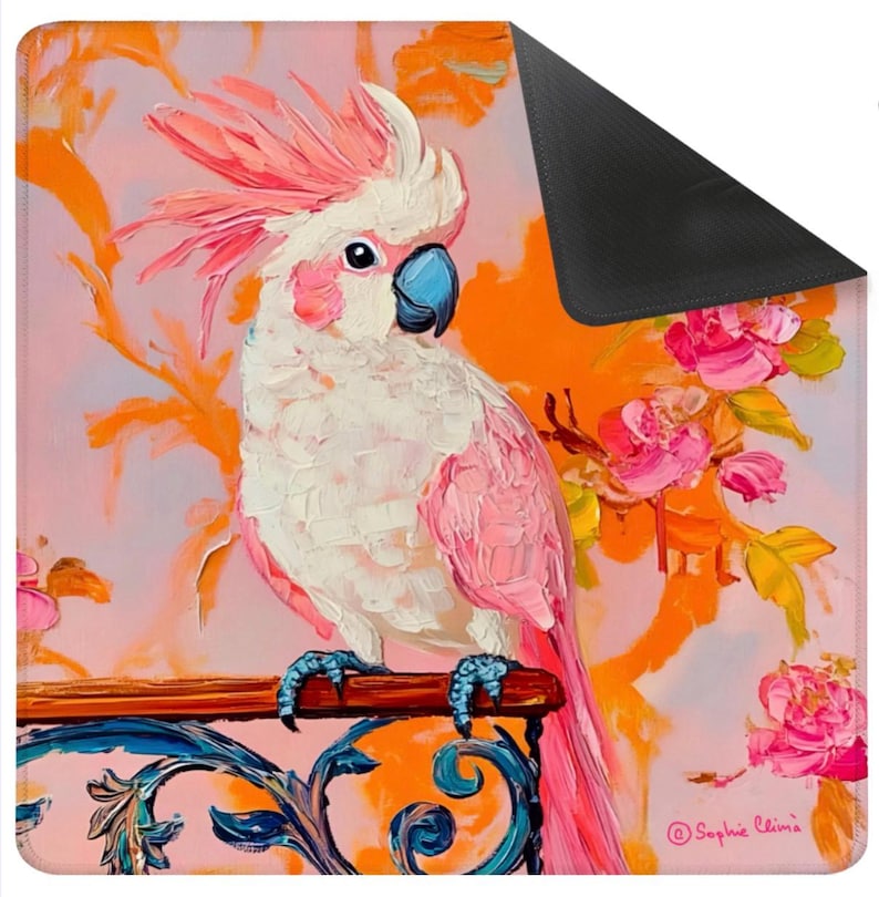 May include: A decorative mat featuring a vibrant painting of a pink and white cockatoo perched on a wooden rail. The background includes orange floral accents and pink roses. The mat has a black border.