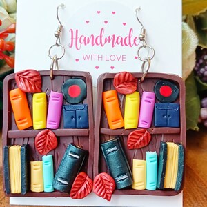 Foglie autunnali su uno scaffale di libri, orecchini fatti a mano in pasta polimerica