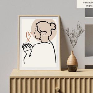 Peut inclure: Impression numérique encadrée représentant un dessin au trait minimaliste d'une personne tenant une tasse, avec un symbole de cœur. L'œuvre est en noir et beige, avec les mots "Instant Download Digital Print" en haut à droite.