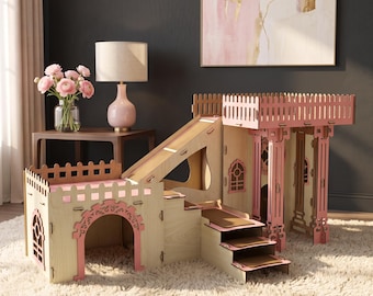 Puede incluir: Una casa de juegos para mascotas de madera de varios niveles con paneles de madera clara y detalles en rosa. La estructura incluye un tobogán, una escalera, puertas arqueadas y una plataforma superior cercada con recortes decorativos.