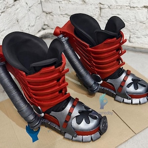 Op de afbeelding: Een paar rode en zilveren laarzen met zwarte details. De laarzen hebben een uniek ontwerp met een bloemvormig detail op de neus.