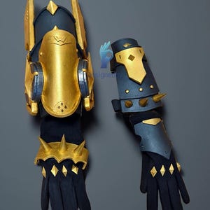 May include: A pair of black and gold cosplay gauntlets. The gauntlets feature gold accents, spikes, and diamond-shaped embellishments. The design includes a navy blue base with gold armor plating and a stylized "W" emblem.