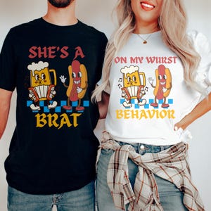 May include: Black and white t-shirts with matching graphics. One shirt says "She's a Brat" with a cartoon beer stein playing an accordion and a hot dog. The other shirt says "On My Wurst Behavior" with the same cartoon characters.