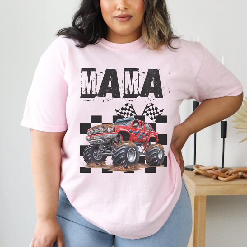 May include: Pink t-shirt with the word "MAMA" in black block letters. A red monster truck graphic is below the text, with checkered flags and a black and white checkered pattern.