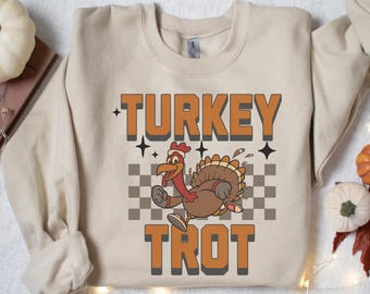 May include: A beige sweatshirt with a cartoon turkey running on a checkered background. The text "TURKEY TROT" is printed in orange on the sweatshirt.